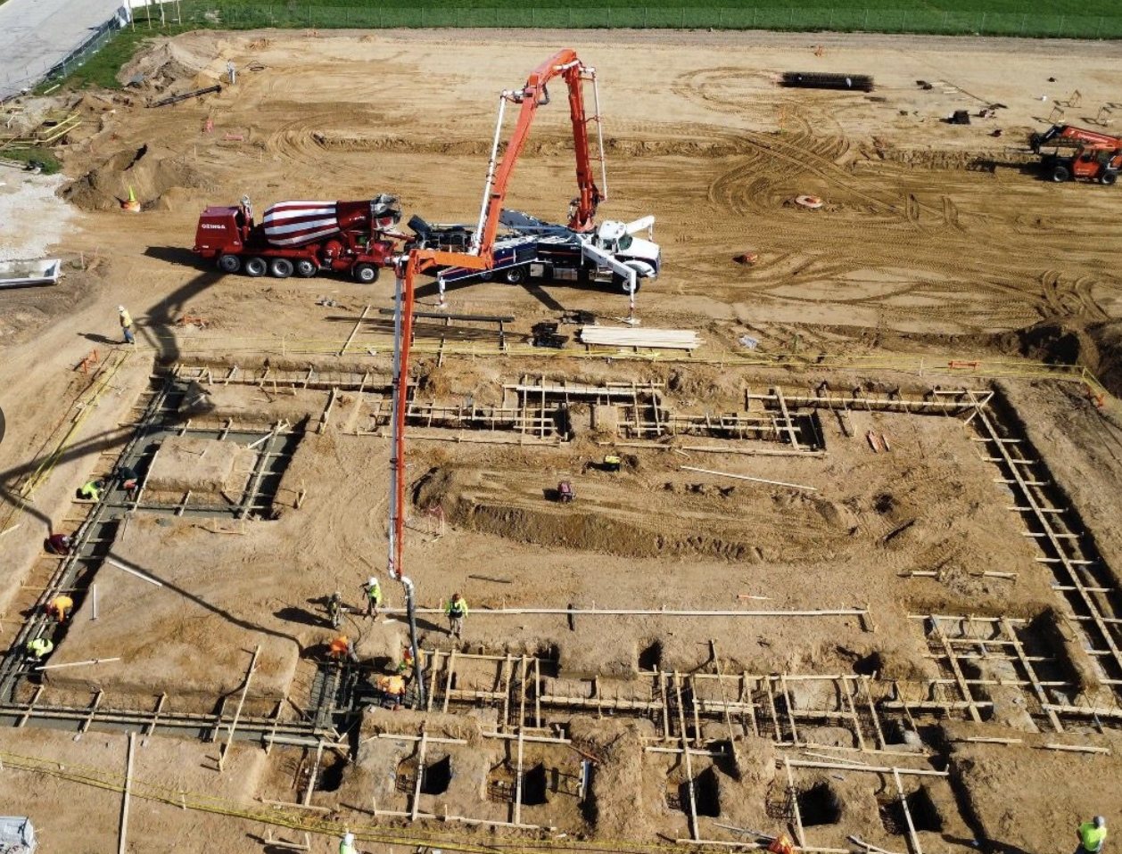 Aerial view of a boom pump placing concrete into engineered footings and foundation walls